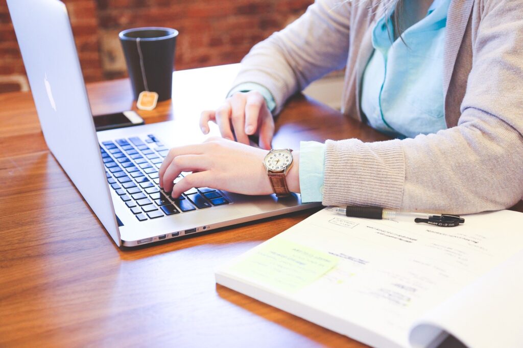 picture of a woman's hands on a laptop with a cup of tea nearby