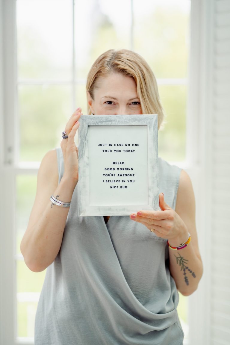 Jane holding a framed print reading "Incase no-one told you today: hello, good morning, you're awesome, i believe in you, nice bum"